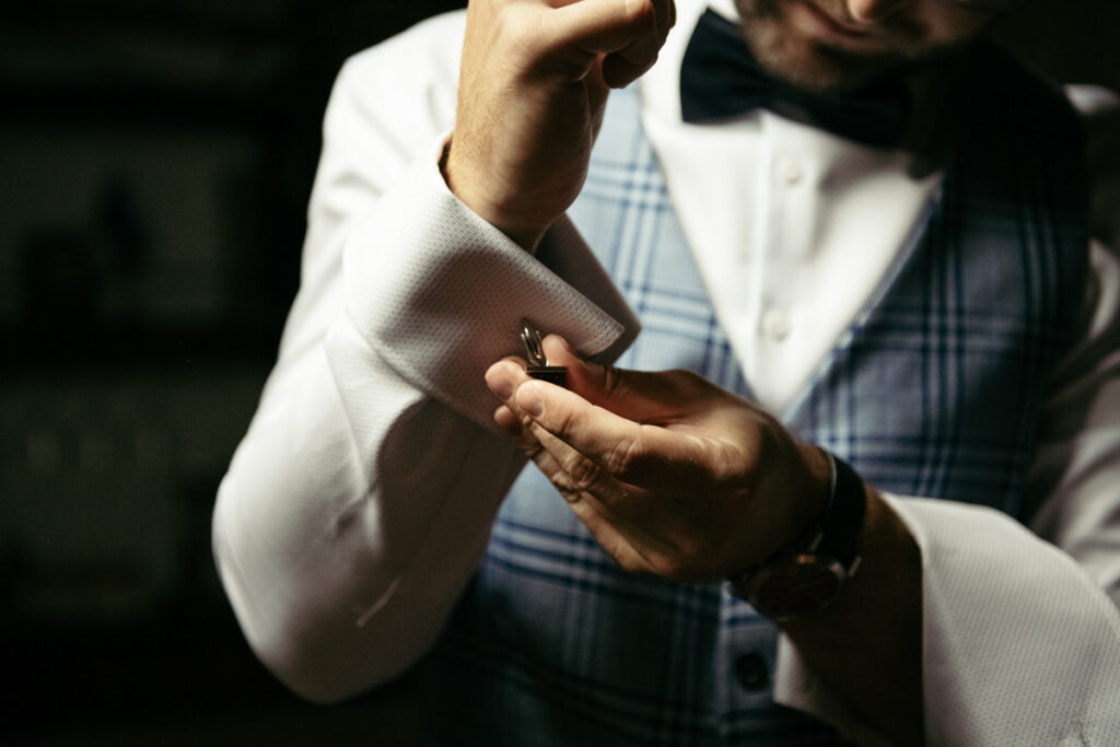 Groom fixing the sleeve of his shirt, highlighting the elegant preparation before the intimate elopement.