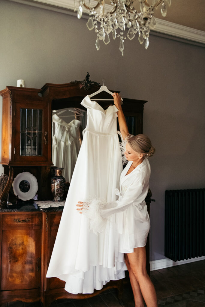 Bride looking at her wedding dress hanging in a rustic room, preparing for her Italian elopement.