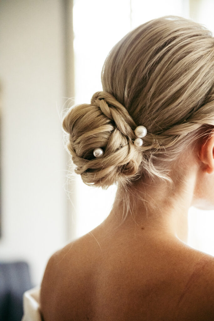 Close-up of the bride’s elegant bun hairstyle adorned with delicate pearl accessories.