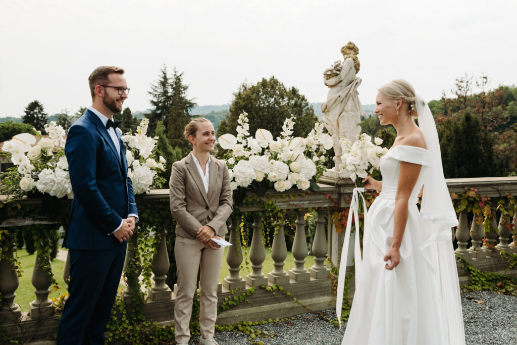 Bride and groom smiling at each other with the celebrant standing beside them during the ceremony.