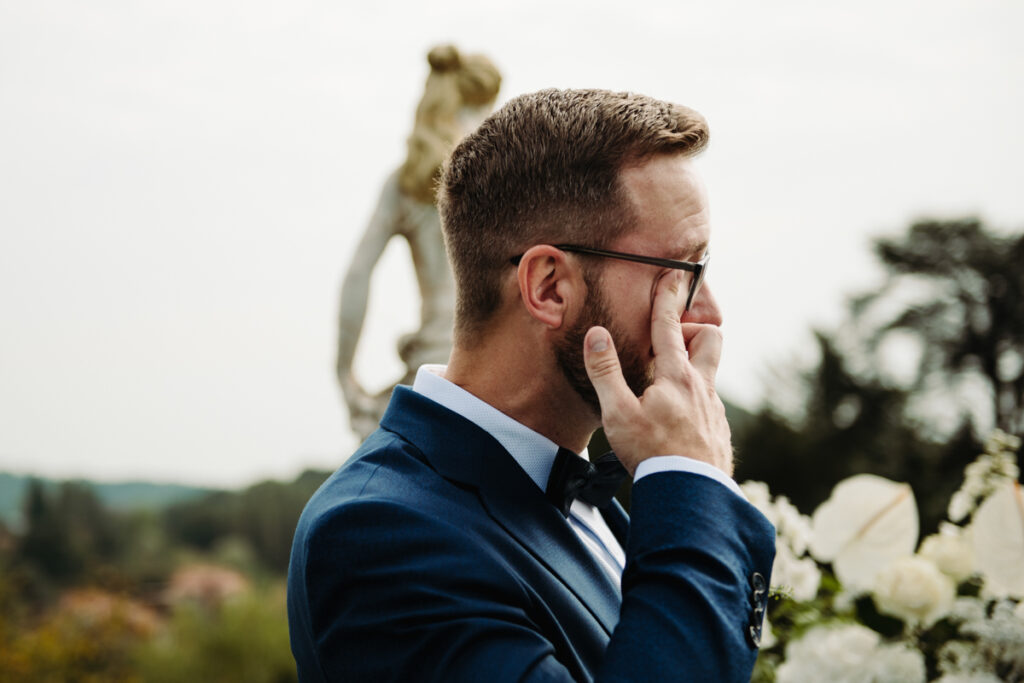 Groom wiping away a tear, visibly emotional during the heartfelt exchange of vows.