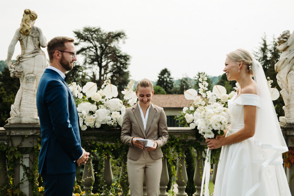 The couple facing each other as the celebrant officiates their outdoor symbolic ceremony.