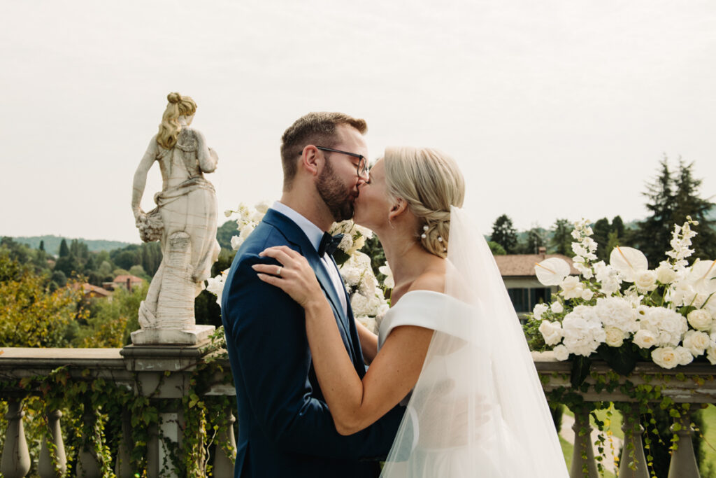 Bride and groom kissing, immersed in the beauty of the Italian landscape.