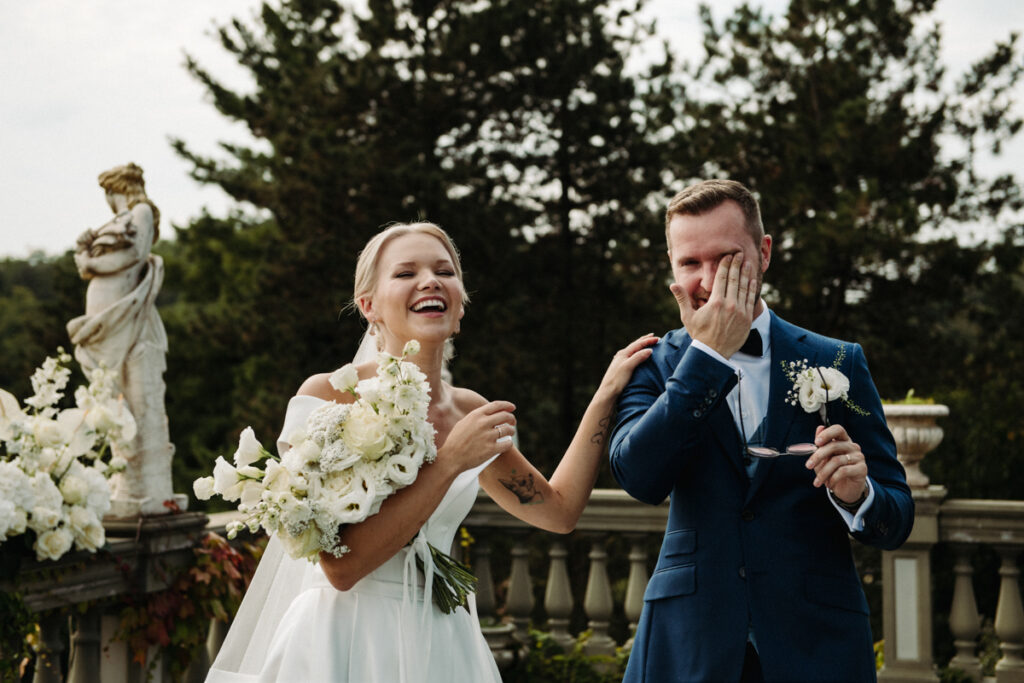 Spontaneous joyful moment: the bride laughs while the groom covers his face, overwhelmed with emotion