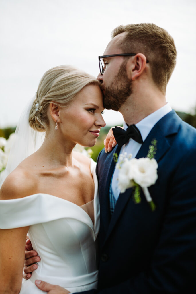 Intimate close-up of the groom gently kissing the bride's forehead during their Italian elopement