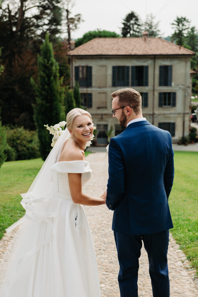 Bride smiling while holding the groom’s hand during an outdoor photoshoot