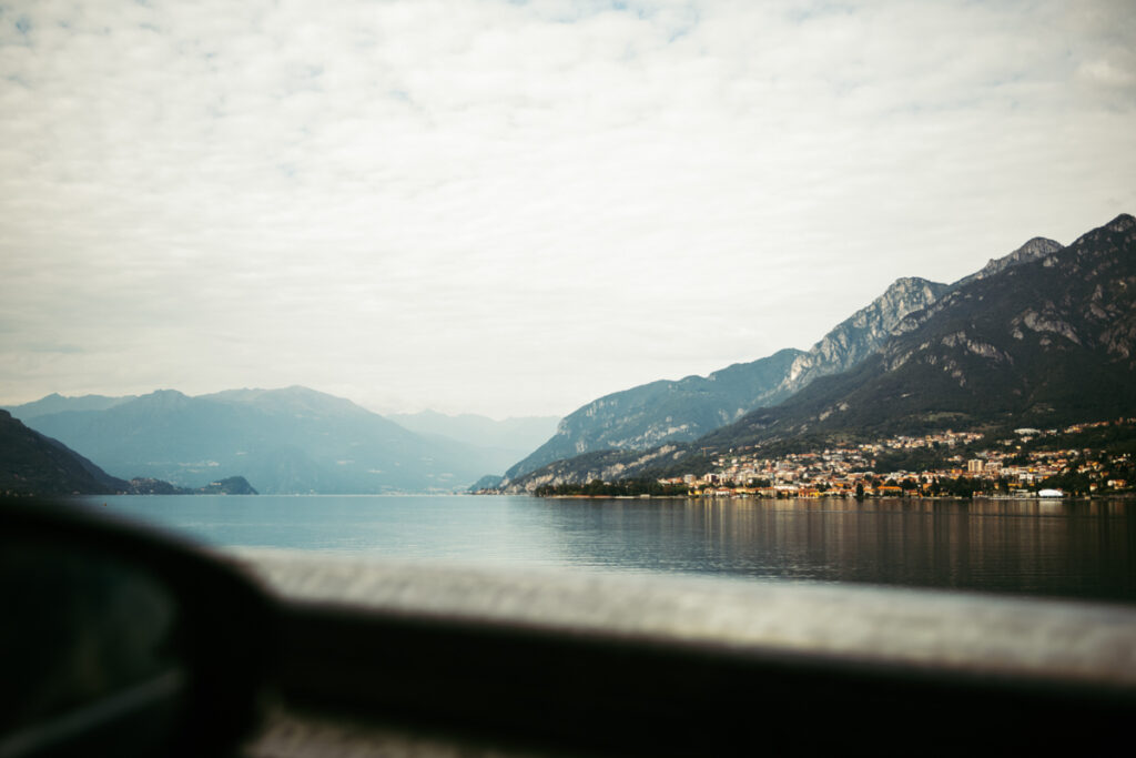 Scenic view of Lake Como framed by a car window, with mountains in the distance