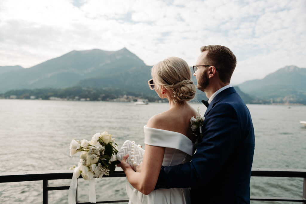 Bride gazing at the lake while holding her bouquet, with mountains in the background