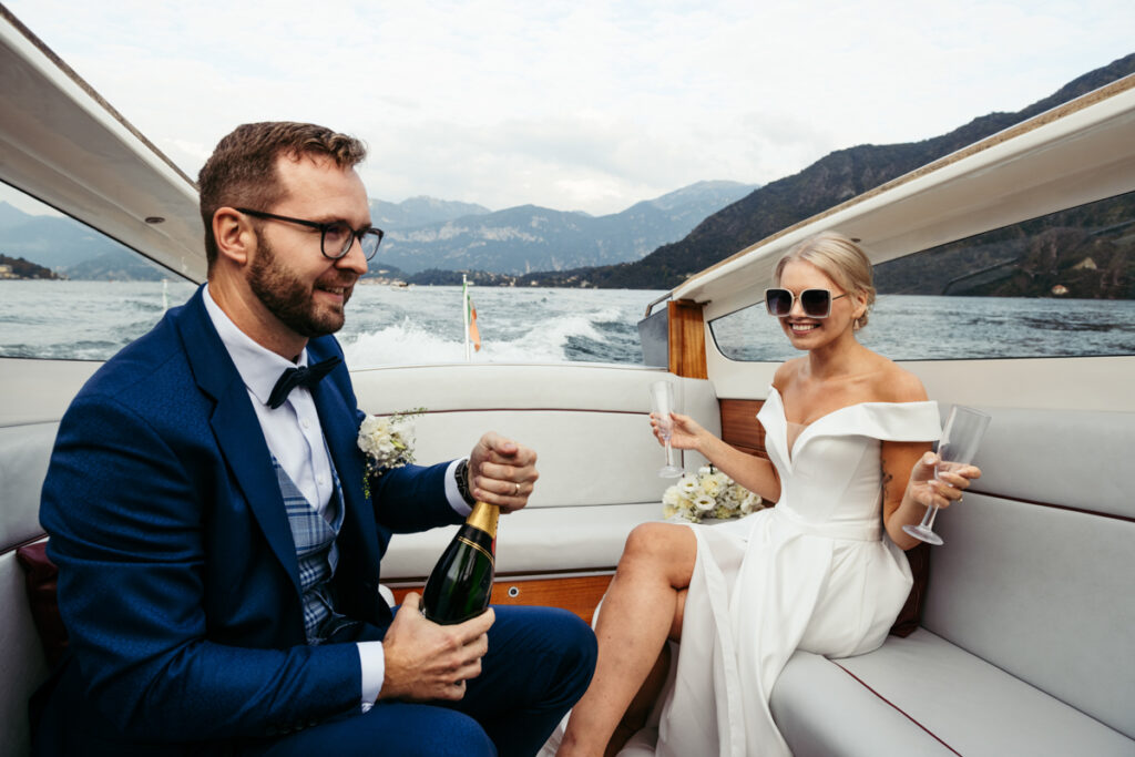 Bride and groom enjoying a relaxed moment on the boat, holding champagne glasses