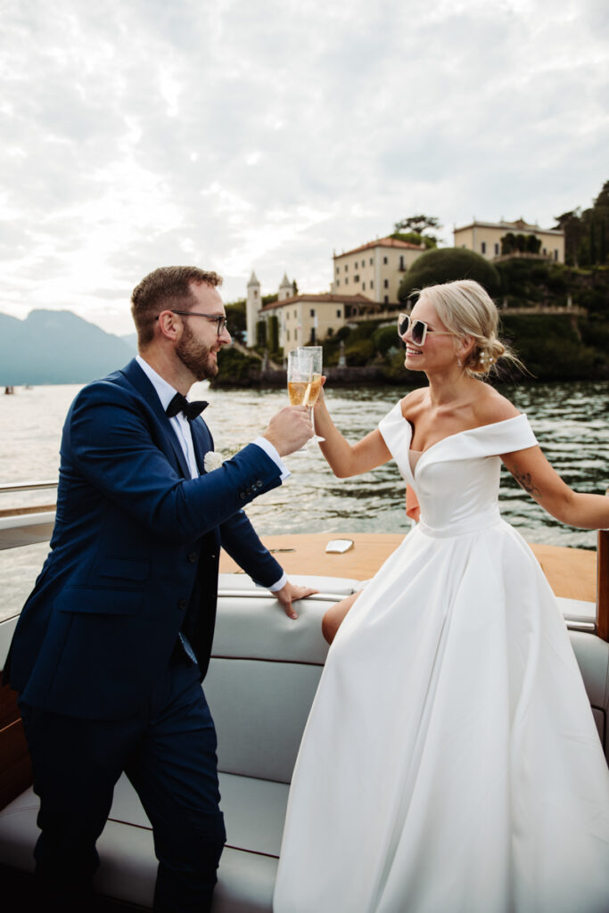 Bride and groom celebrating with champagne on their private boat in Lake Como