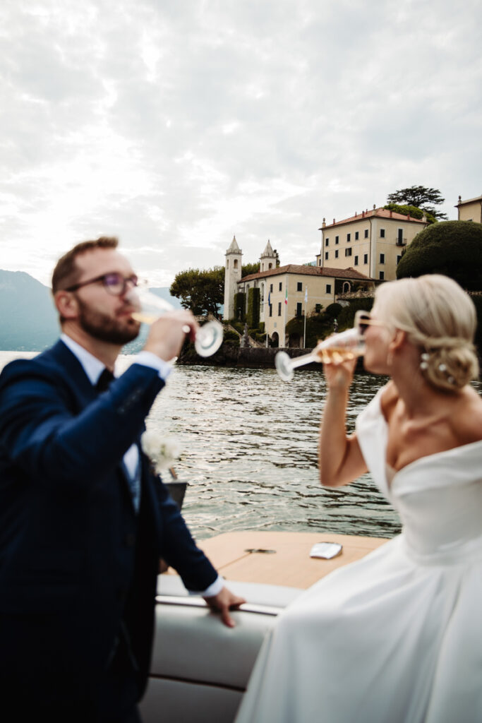 Bride and groom drinking champagne, smiling at each other during their boat ride