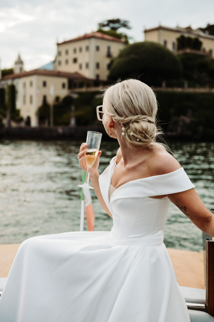 Bride sipping champagne while admiring the view of Villa del Balbianello from the boat