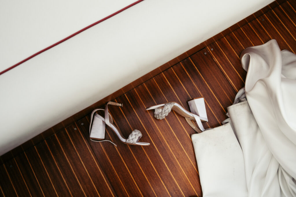 Bride’s shoes left on the wooden deck of a boat