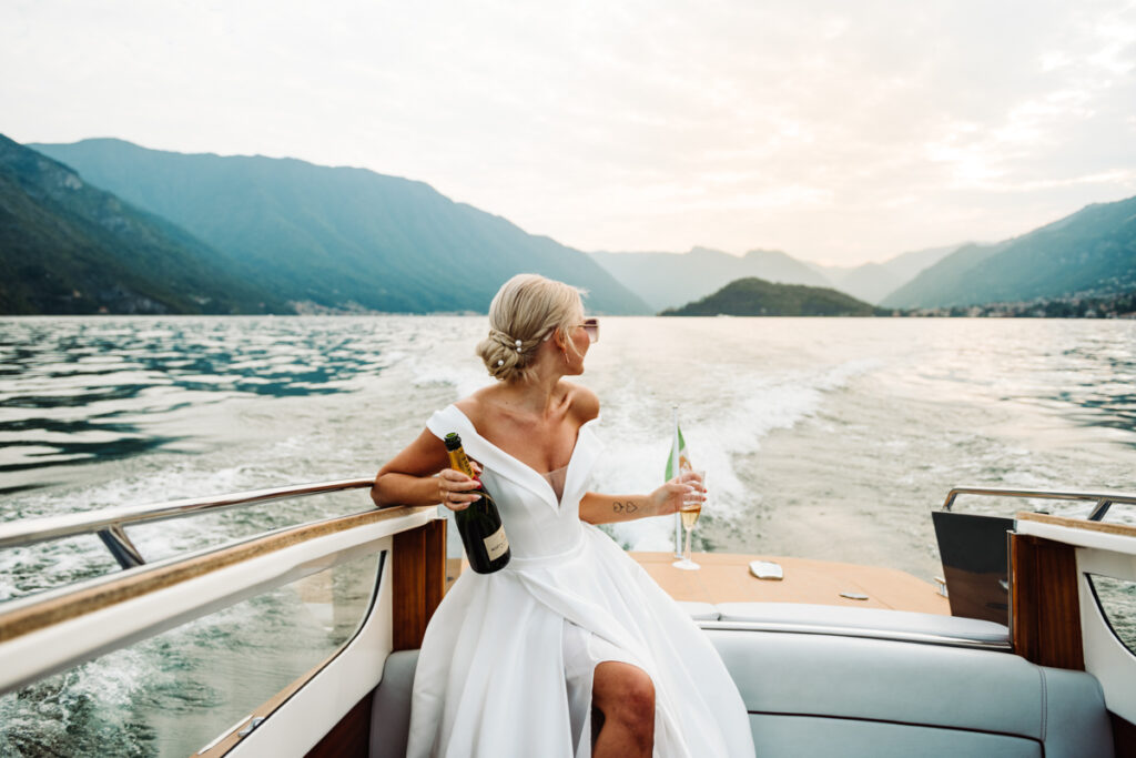 Bride relaxing on a boat, enjoying the breeze and holding a bouquet while sailing on Lake Como