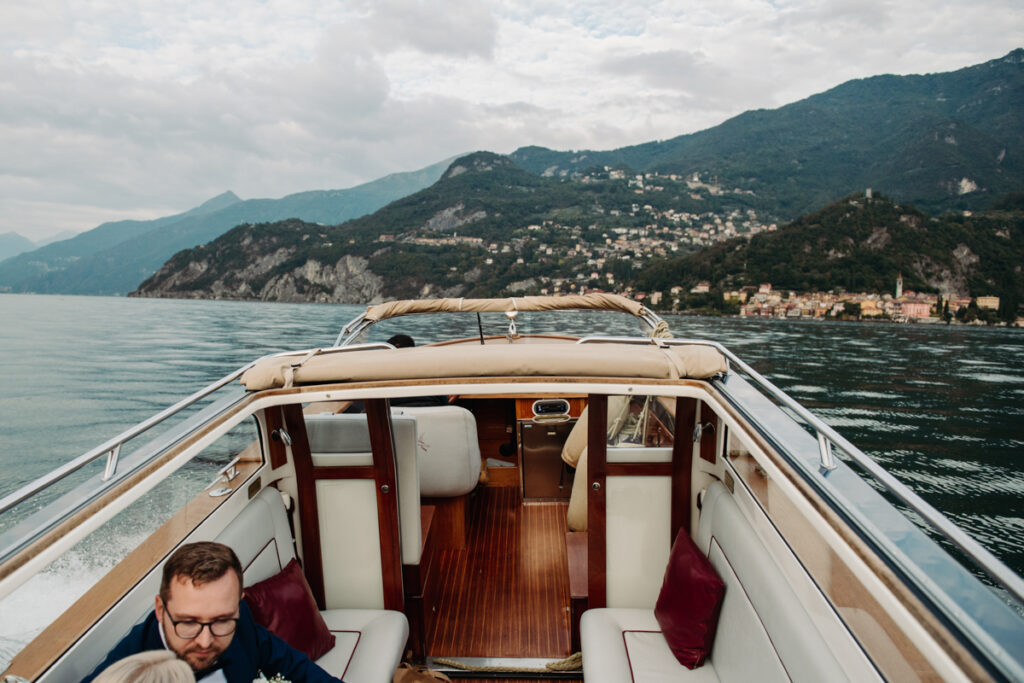 Rear view of a classic wooden boat cruising on Lake Como, with mountains in the distance