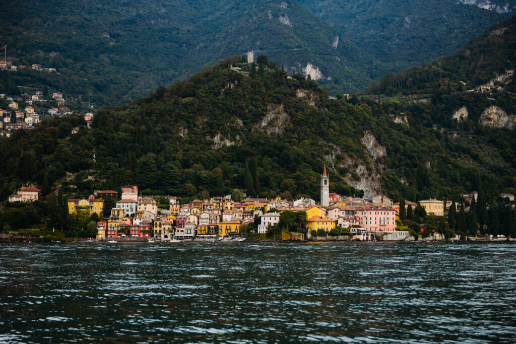 Vibrant lakeside town with lush green hills and boats floating on Lake Como