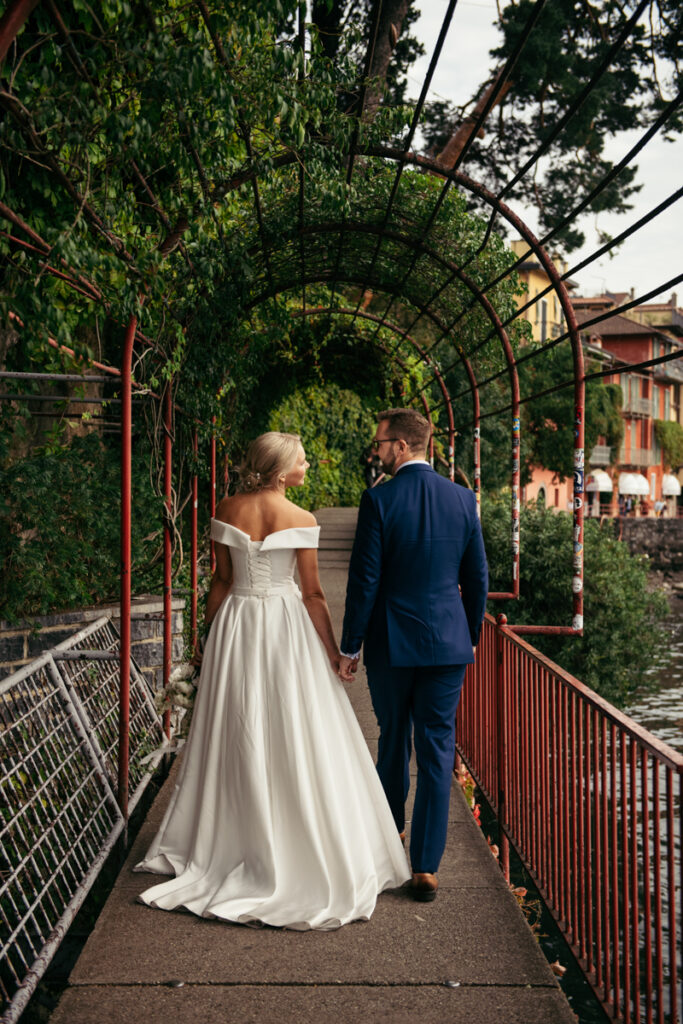 Bride and groom walking hand in hand under a romantic archway covered in greenery