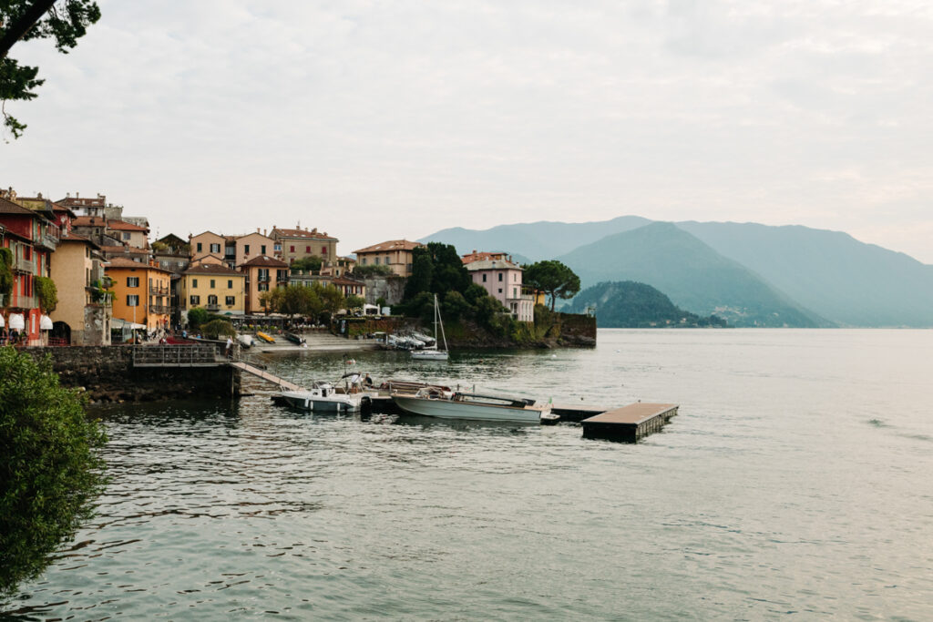 Scenic view of a lakeside town with boats docked along the shore of Lake Como, taken from Varenna