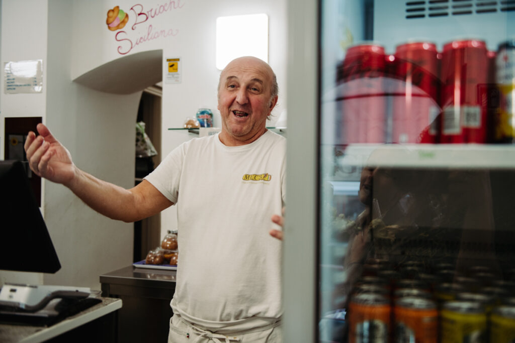 Friendly gelato vendor smiling inside a local Italian shop