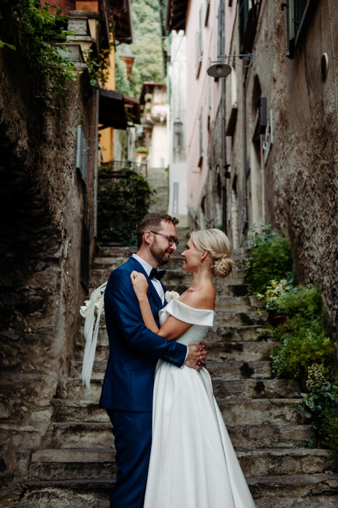 Bride and groom sharing an affectionate moment in a charming alleyway with stone walls