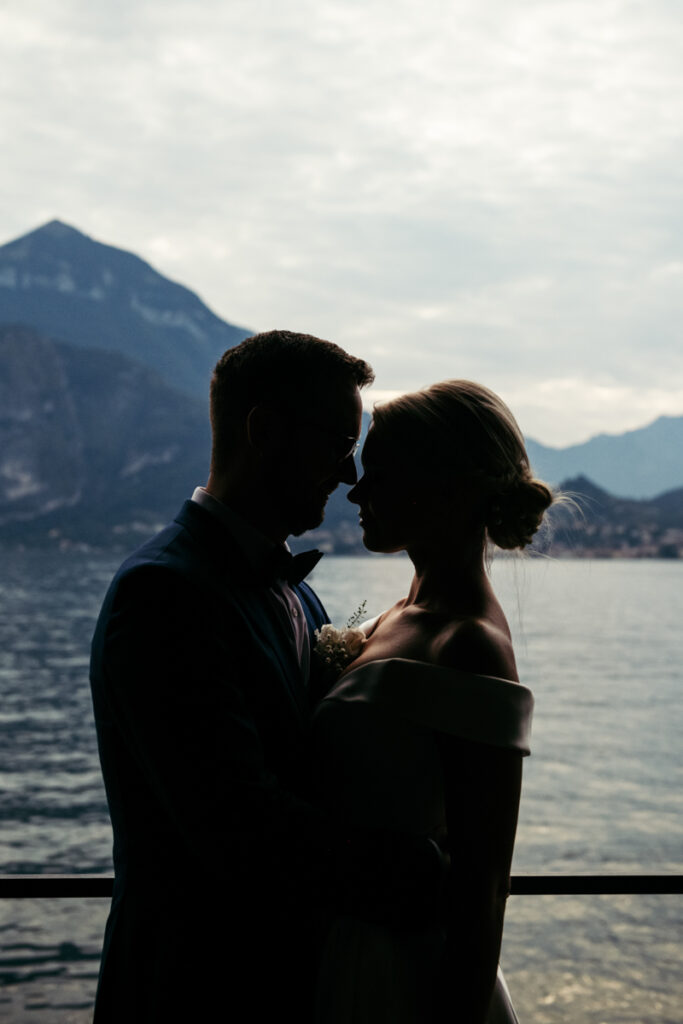 Silhouette of the bride and groom gazing at each other against the backdrop of Lake Como’s mountains.