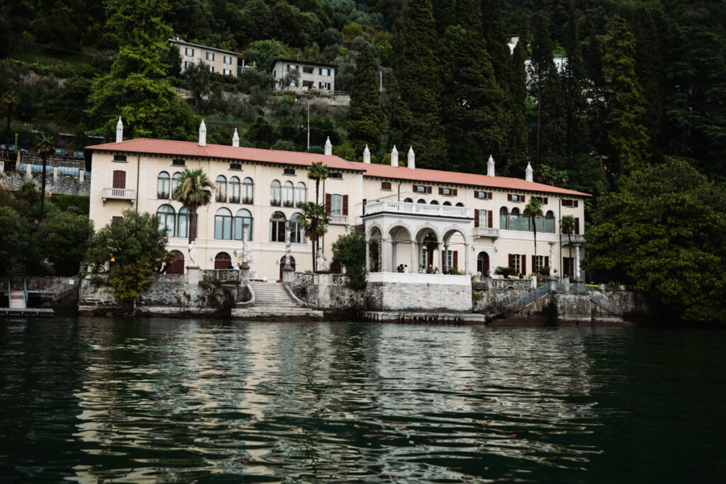 View of a lakeside villa surrounded by greenery, reflected on the waters of Lake Como