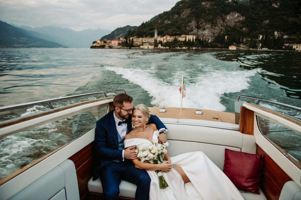 Bride and groom sitting on a boat, hugging while cruising on Lake Como