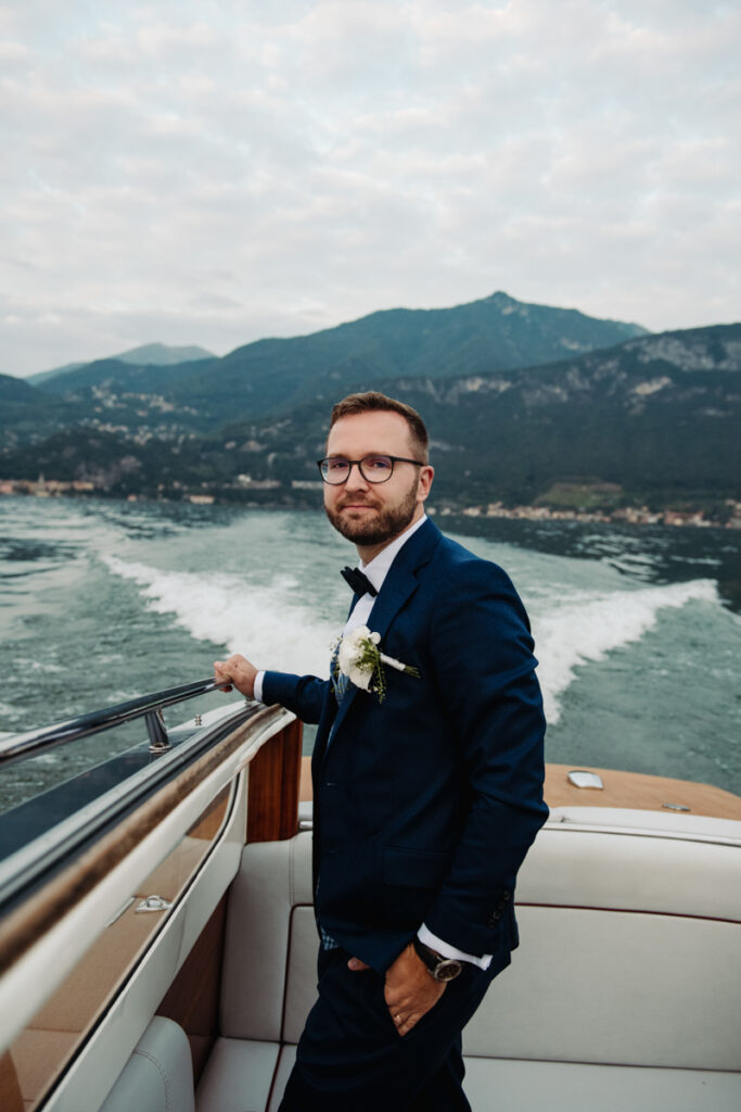 Groom standing on a boat, looking in the camera.