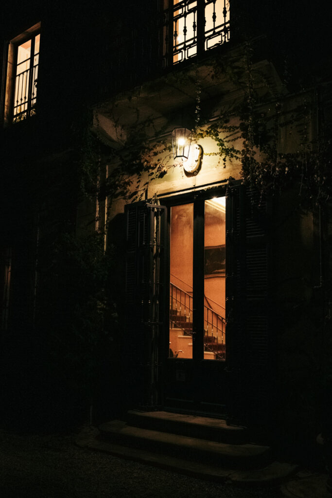 Cozy evening view of a warmly lit villa entrance surrounded by ivy.