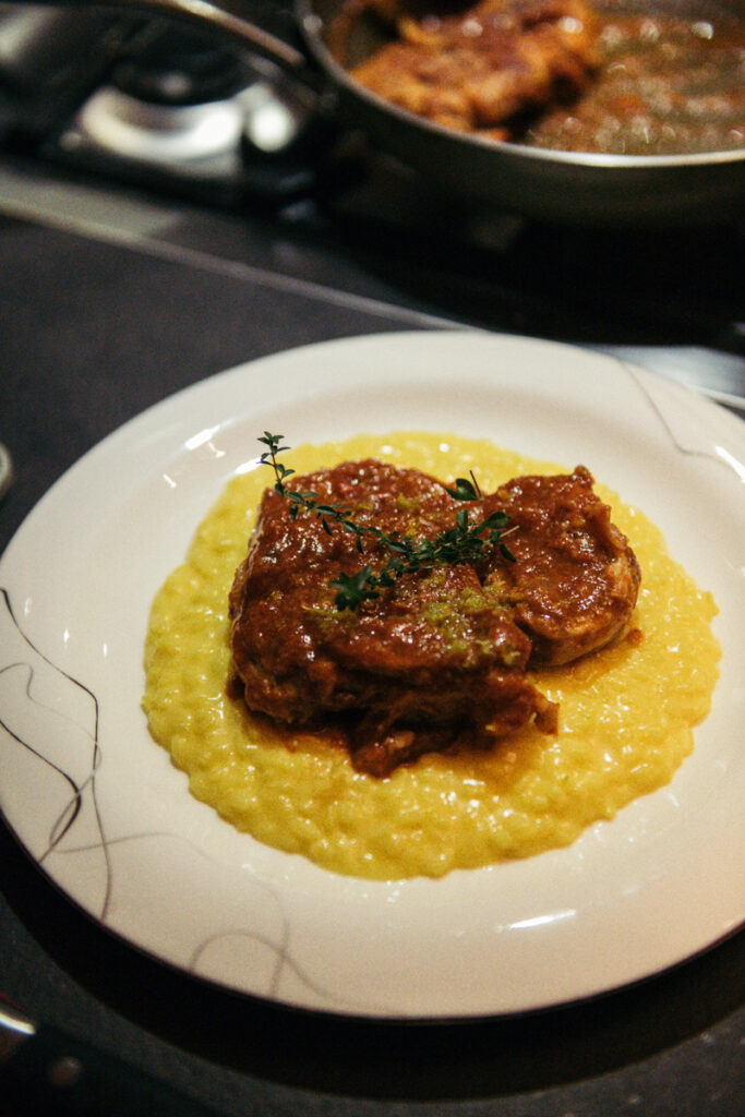 Close-up of a plated Italian dish, featuring osso buco with saffron risotto.