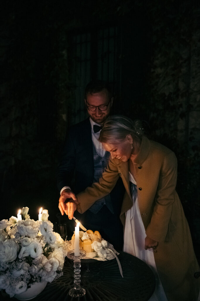 Bride and groom cutting a cake together during an outdoor evening celebration