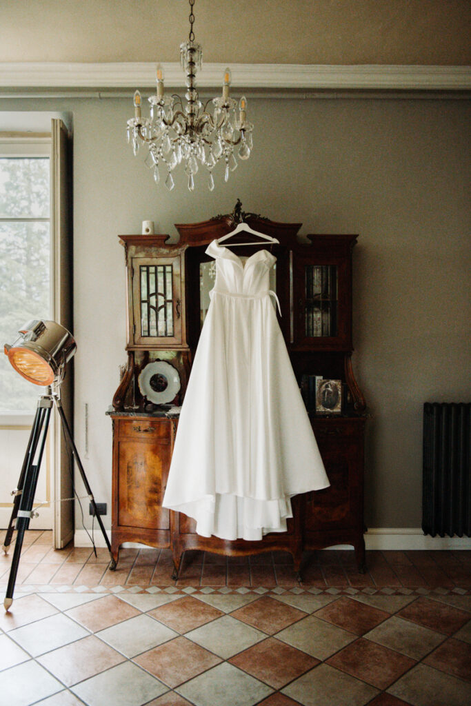 Wedding dress hanging elegantly in a room with vintage furniture