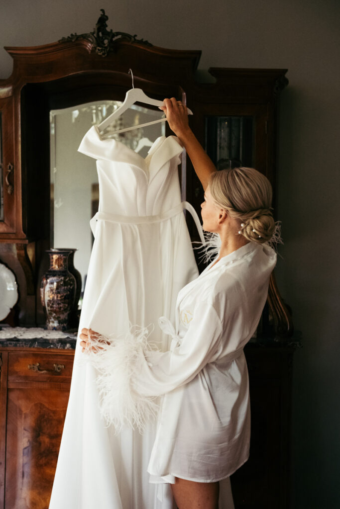 Bride holding her wedding dress, admiring it before getting dressed