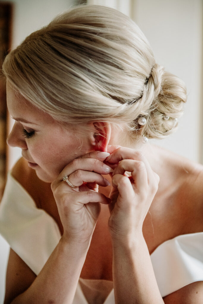 Close-up of the bride putting on an earring while getting ready for the ceremony