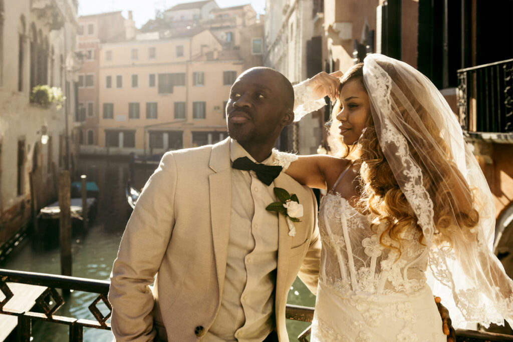 Newlyweds sharing a joyful moment in the golden light of Venice, with romantic architecture in the background.