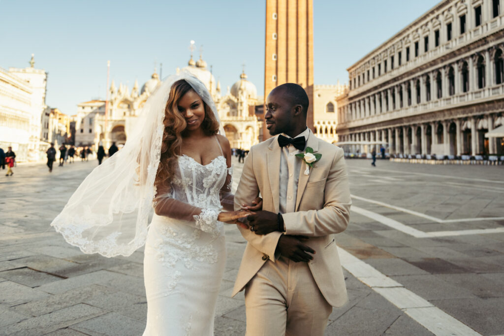 Elegant wedding couple walking together in Piazza San Marco, Venice.