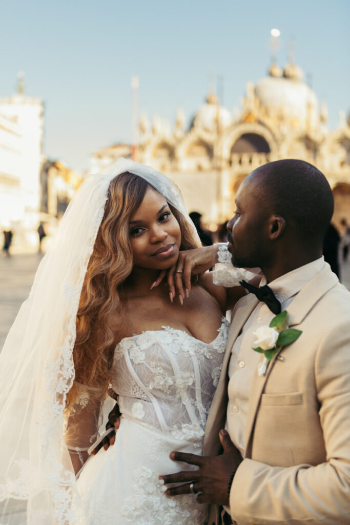 Bride and groom smiling in front of St. Mark’s Basilica in Venice, Italy.