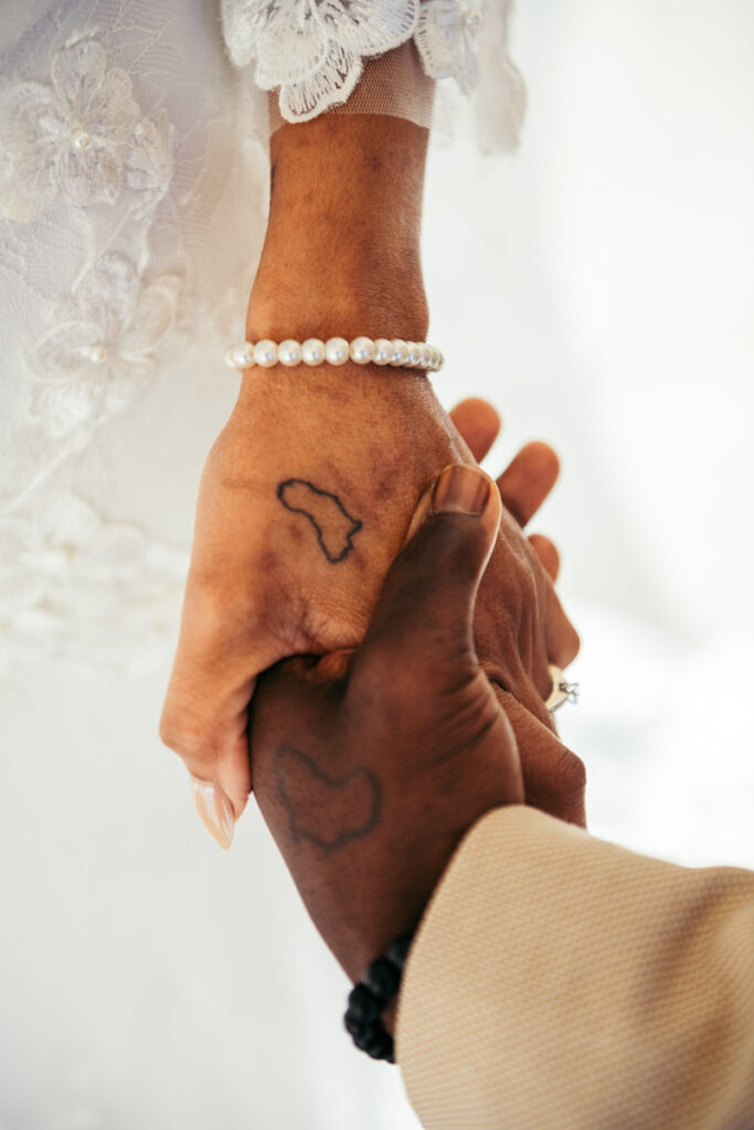 Close-up of a couple holding hands, showing matching tattoos of the African continent.