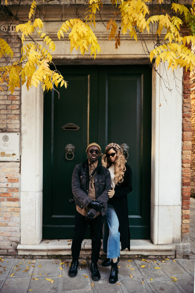 Close-up of a couple wearing sunglasses, leaning against a green door.