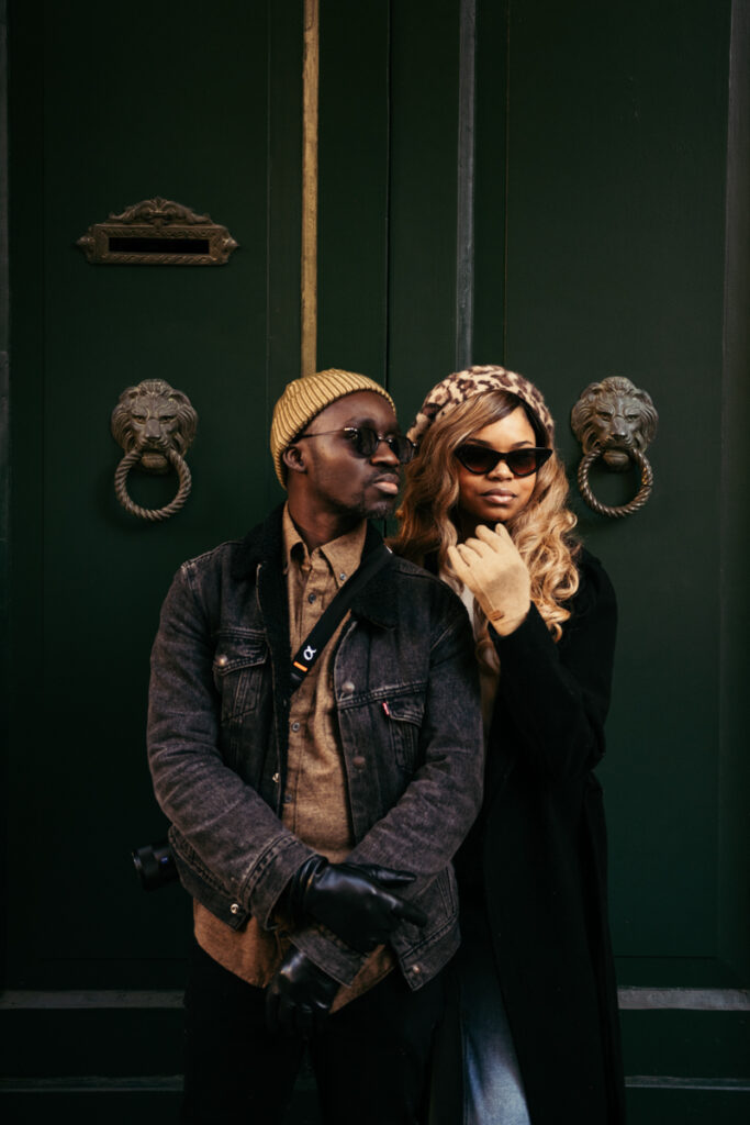 Couple standing in front of a green door in Venice, wearing stylish outfits.