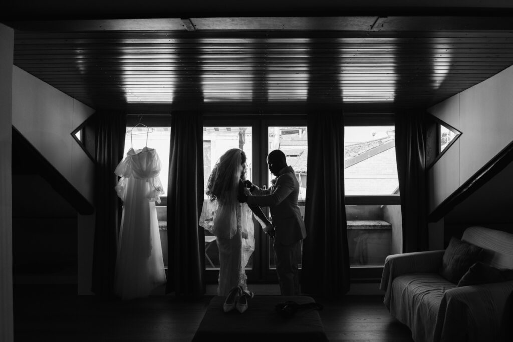 Black and white silhouette of a couple sharing a tender moment in a Venetian hotel room.
