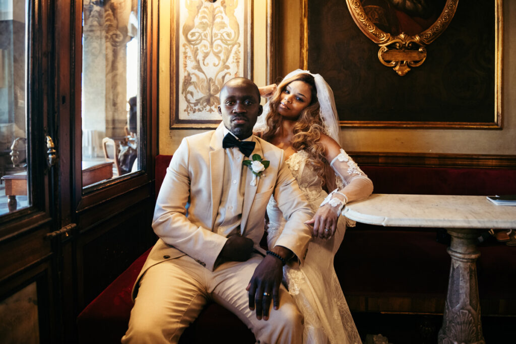 Elegant bride and groom enjoying a quiet moment inside a Venetian café.