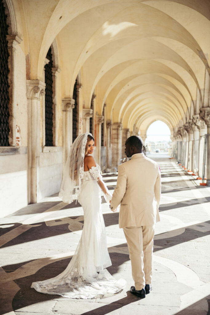 Newlyweds sharing a romantic gaze under the historic colonnade in Venice.