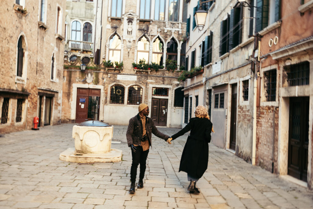 Couple strolling through a charming Venetian square, hand in hand.