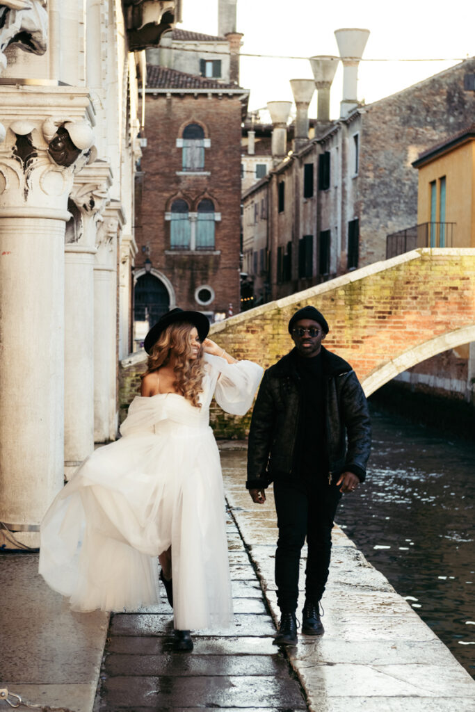 Groom and his bride walking near a canal in Venice.