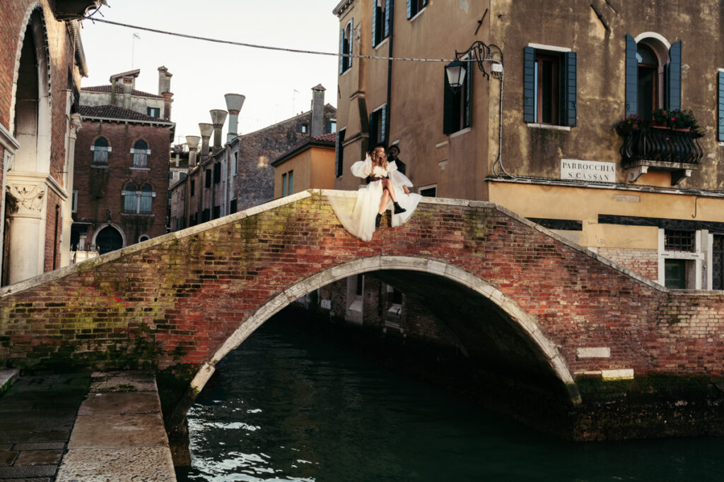 Couple sitting on a picturesque Venetian bridge.