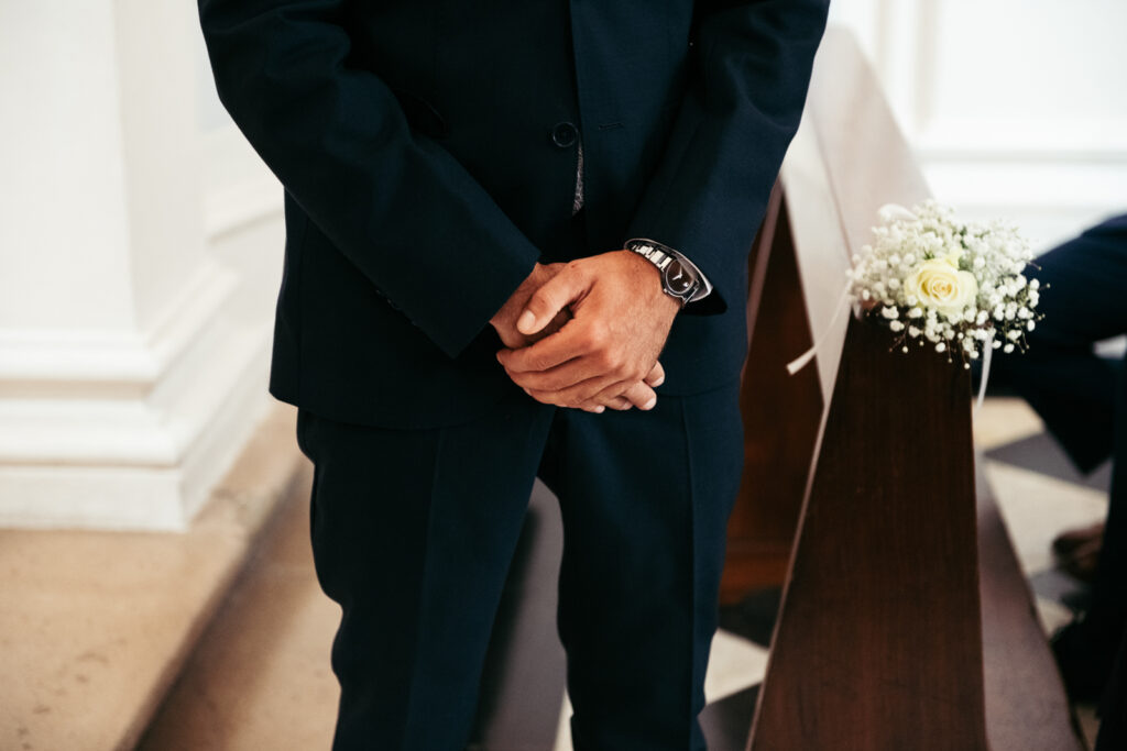 Detail of the groom’s hands as he waits nervously in the chapel aisle.