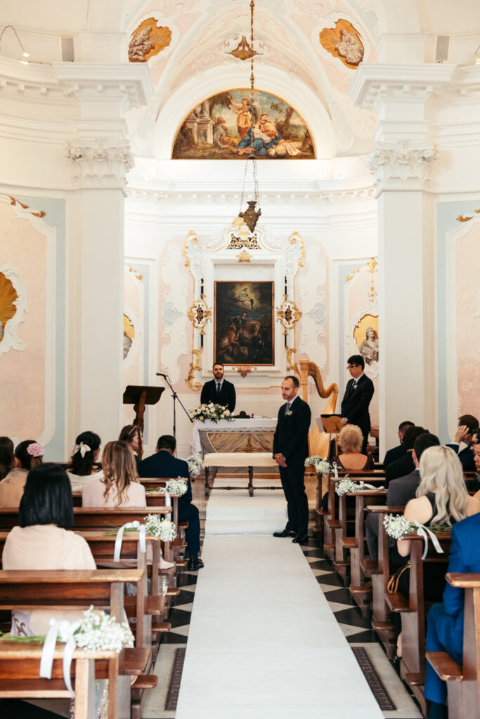 Bride entering the chapel as guests stand for the start of the intimate wedding ceremony.