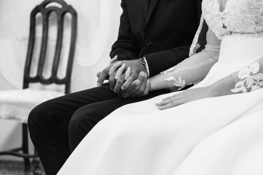 Black and white close-up of the couple holding hands during the ceremony.