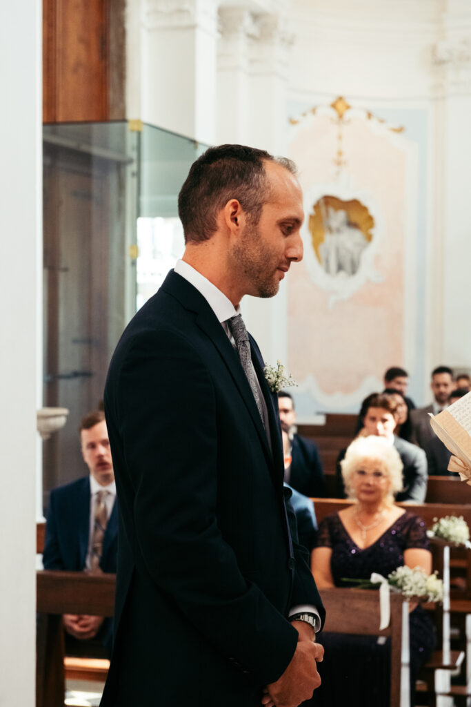 Groom smiling at the bride as she reads her vows during their intimate ceremony.